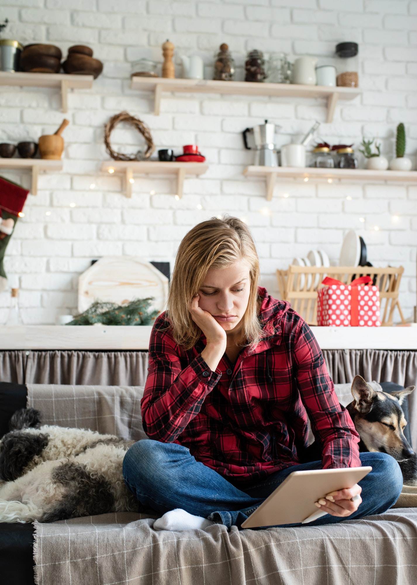 young sad woman working on tablet sitting on the couch